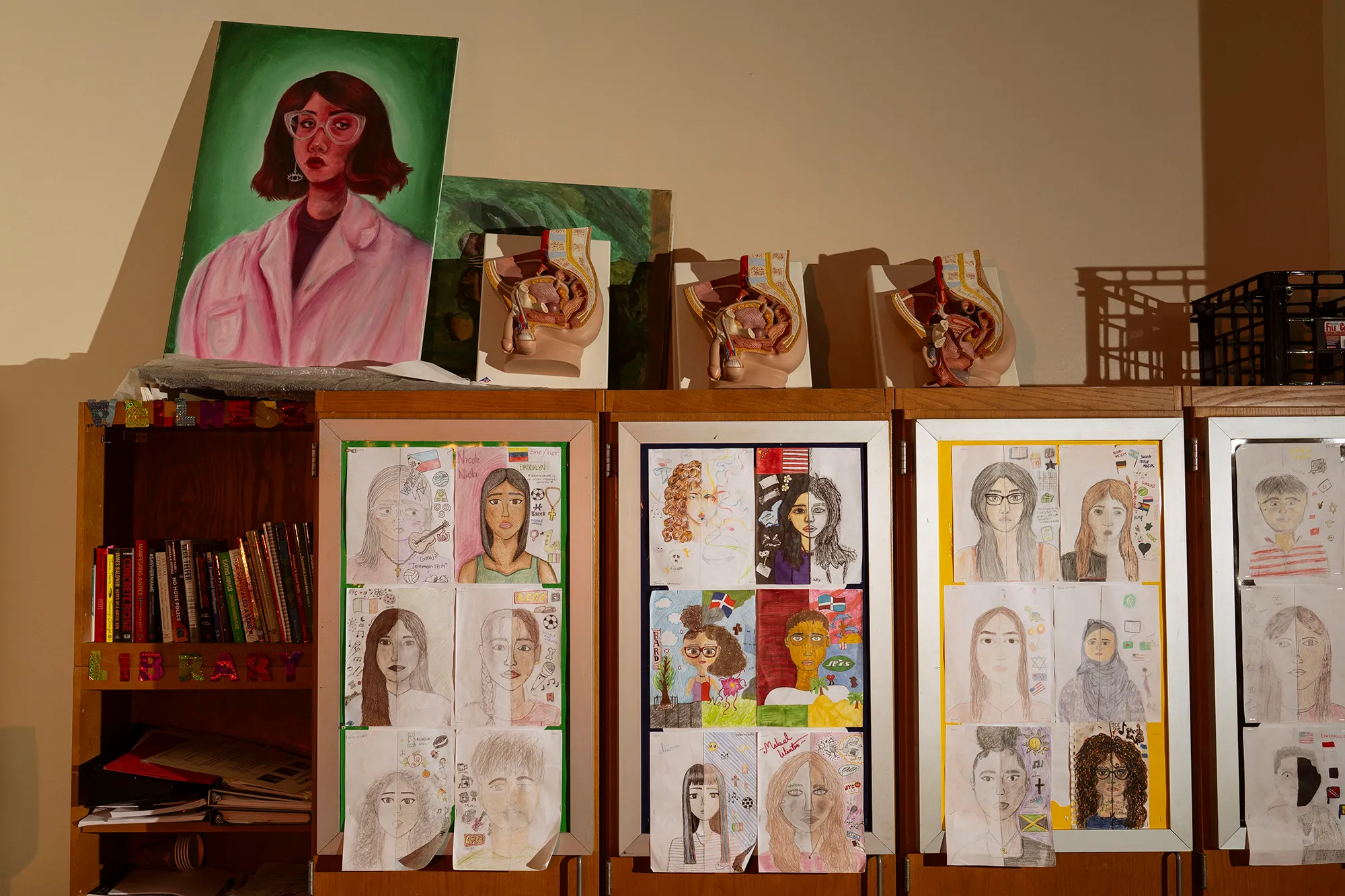Cabinet with student drawings taped to the front and anatomical models on top.